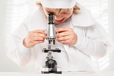 studing boy with a microscope on a window background.の写真素材