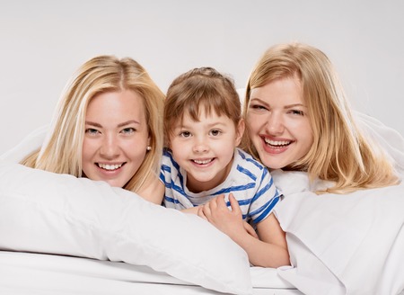 Portrait of a joyful relations in the bed on light grey backgroundの写真素材