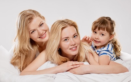 Portrait of a joyful relations in the bed on light grey backgroundの写真素材