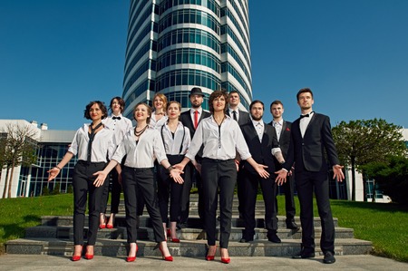 cheerful friends dressed tuxedo in the summer city on stairs. there is modern building behindの写真素材