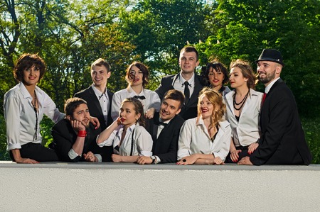 sitting cheerful friends dressed tuxedo in the summer city. green trees are backgroundの写真素材