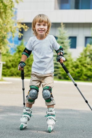 young boy on roller skates outdoors.  beginner. with nordic walking polesの写真素材