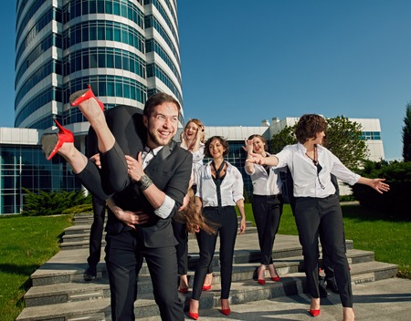 cheerful friends dressed tuxedo in the summer city on stairs. there is modern building behindの写真素材
