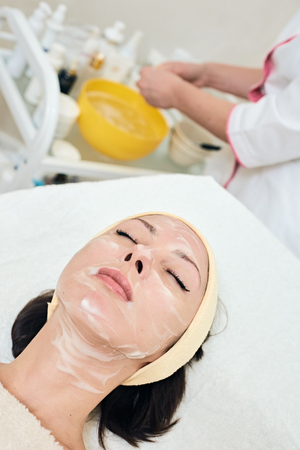 young woman is on procedure of cleansing, enzyme peeling. background with cabinet and hands of doctorの写真素材