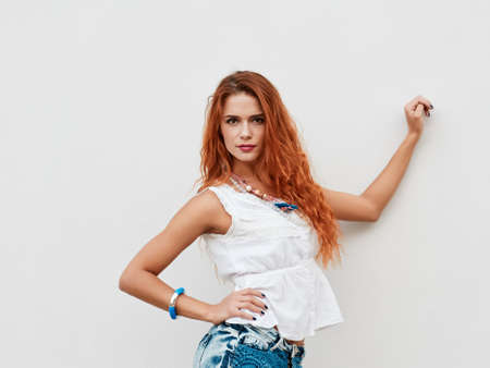 Beautiful and happy young woman standing against wall