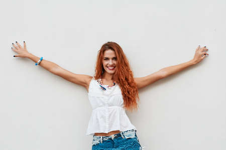 Beautiful and happy young woman standing against wall