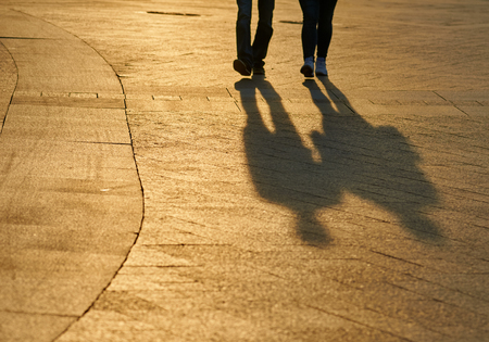 blurred background summer park with people and those shadows. focus is on Pavement foreground....