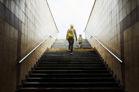 mother and son walks up stairs to toward the light at the top. Concept of success stairs.の写真素材