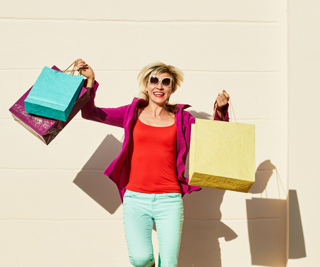 Beautiful woman with shopping bags about the wall with shadowの写真素材