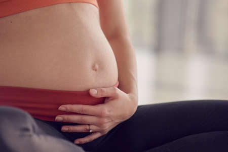 Young pregnant woman sitting on floor, part of bodyの写真素材