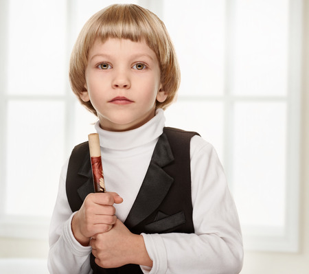 Cute little boy playing wood fife. Preschooler. on light window backgroundの写真素材
