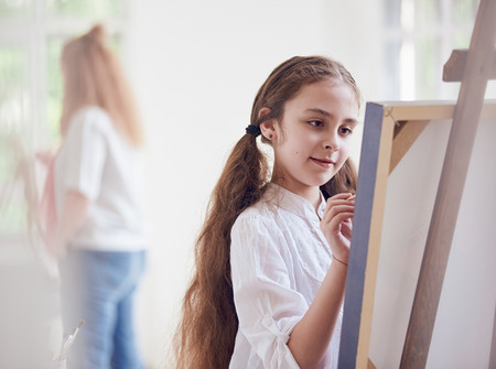 Long-haired girl artist about canvas with brushesの写真素材