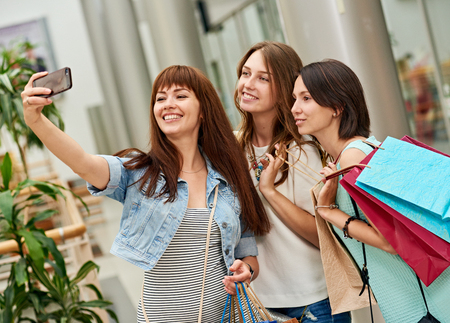 Beautiful girls with shopping bags taking a selfie their cell phoneの写真素材