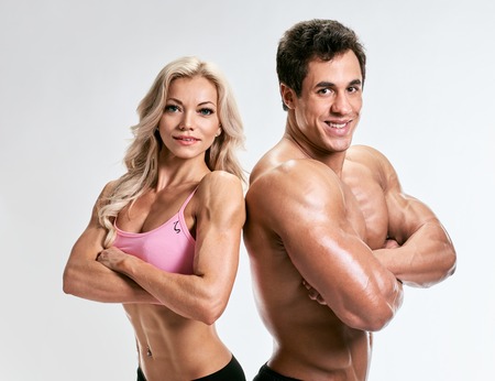 Couple man and woman muscled. bodybuilders portrait on grey backgroundの写真素材