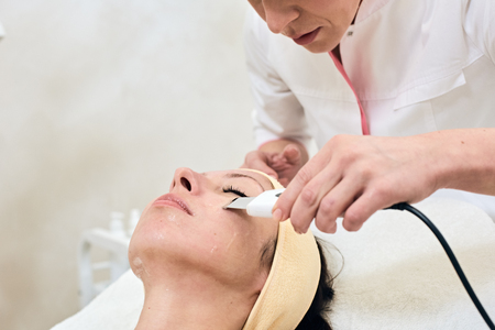 Young pretty woman receiving treatments in beauty salons. Ultrasonic cleaning procedure. Hardware cosmetology. ultrasonic peelingの写真素材