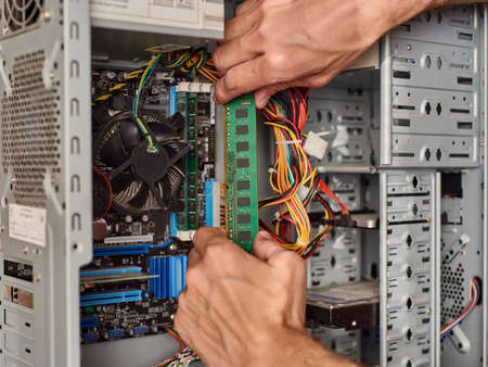 Close up of male hands connecting ram Memory card chip with computerの写真素材