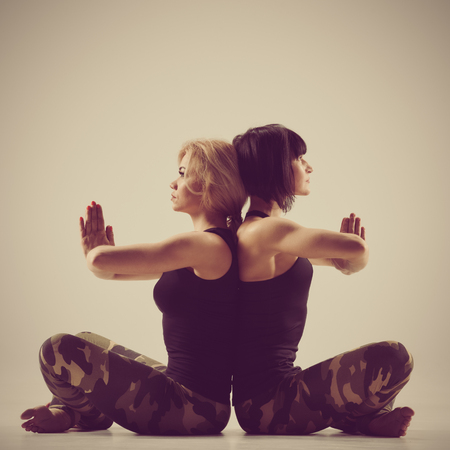 Two young women practicing yoga poses and asanas. image with vintage toningの写真素材