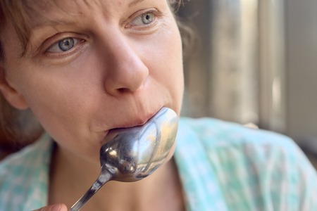 Woman licking spoonの写真素材