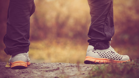 Male legs standing on autumn grass with yellow fallen leaves. image with vintage toning