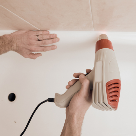 Closeup of male hands drying gaps in bathroom with special toolの写真素材