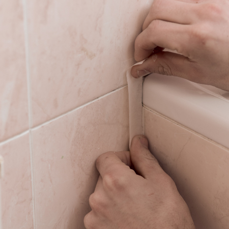 Closeup of man gluing adhesive tape on pipe in bathroomの写真素材