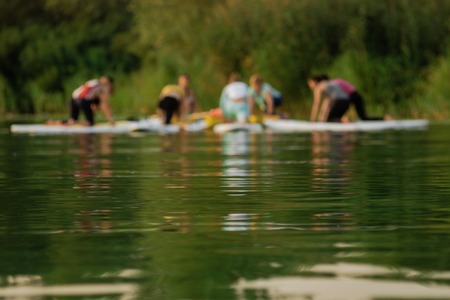 Blurred photo of group practicing sup yoga on riverの写真素材