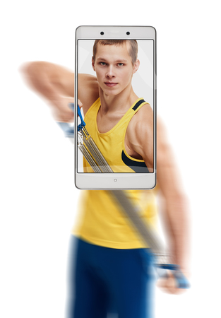 Photo of concentrated young sporty man working out with expander. conceptual image with a smartphone, demonstration of device capabilitiesの写真素材
