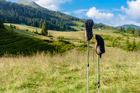 Shoes on trekking sticks against beautiful mountain background