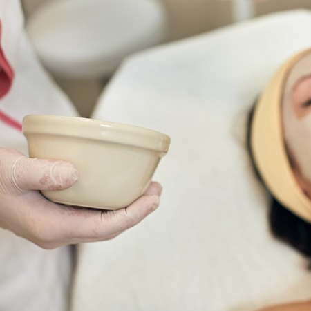 Closeup photo of professional beautician applying peeling scrub on female faceの写真素材