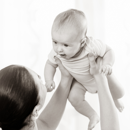 Young mother playing with her newborn cute baby, black white image with bit toning
