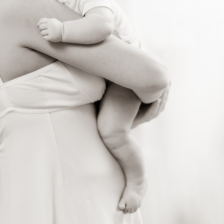 Closeup photo of woman with long hair holding her little baby, black white image with bit toningの写真素材