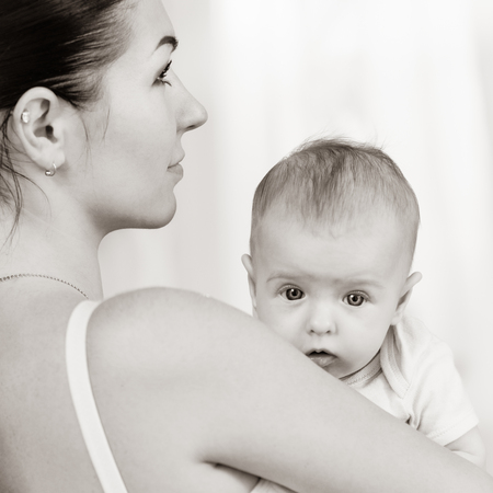 Portrait of young loving mother holding her newborn child, black white image with bit toningの写真素材