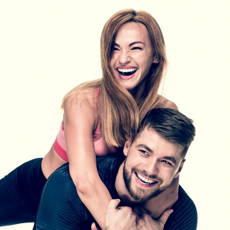 Portrait of cheerful athletic man carrying his laughing woman on back, image with warm vintage toningの写真素材