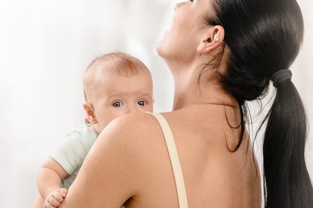 Closeup photo of young mother holding her sweet baby at home