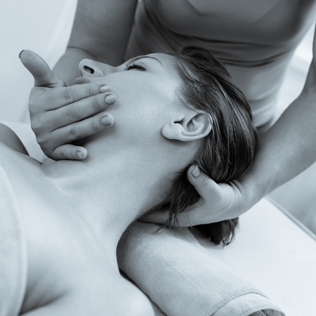 Top view photo of young woman having neck massage. photo converted in black and white with a blue tintの写真素材