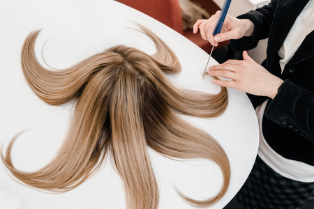 hairdresser makes hairstyle, dye on special disk at a beauty salon. Hair covered in dyeの写真素材