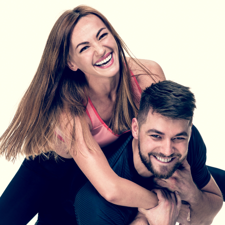 Portrait of cheerful athletic man carrying his laughing woman on back, image with warm vintage toningの写真素材
