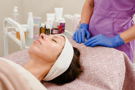 Woman with gel on face in beauty salon, cosmetologist waiting for absorbationの写真素材