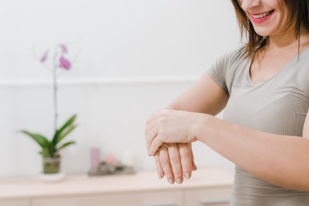 Closeup photo of female masseur stretching hands on the background of modern office