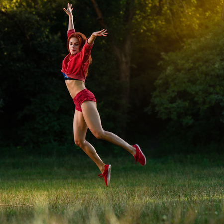 Slim sporty woman warming up and jumping at morning in parkの写真素材