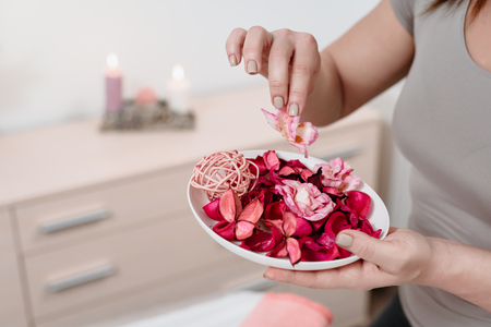 Closeup of female masseur preparing for spa procedure with red rose petalsの写真素材