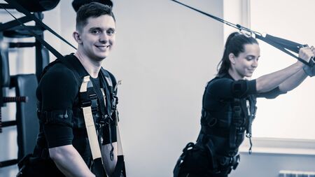 Man and woman in EMS suits doing suspension trainingの写真素材