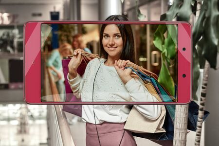 Photo of attractive shopping woman with bags, concept of new features in smartphone s camera