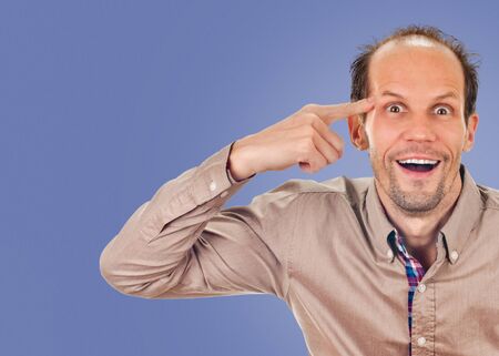 young man gesturing with his finger against his temple. on blue color background