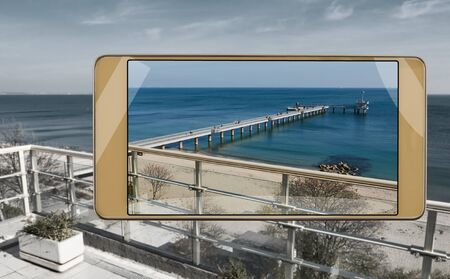 Smartphone displaying photo of sea and pier in Burgas, saturated image in smartphone s camera