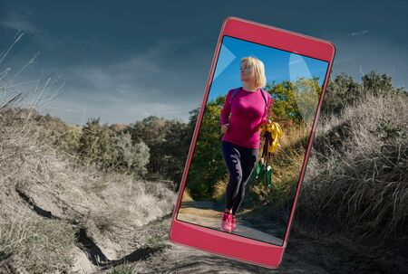 Smartphone displaying photo of fit young sportswoman with equipment going to trainingの写真素材