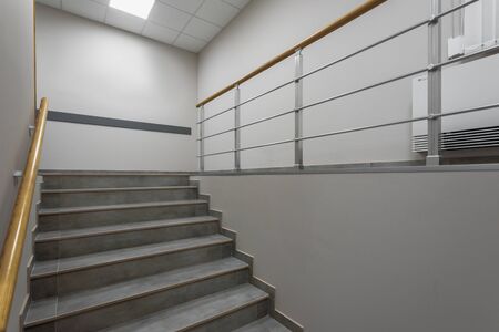 Background of gray staircase with wooden handrail in office building