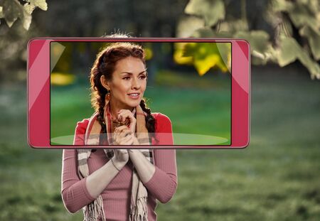 Smartphone displaying photo of happy smiling pretty girl posing outdoors