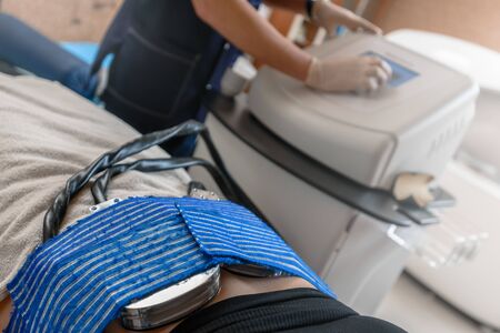 Closeup of client getting cryolipolysis fat treatment procedure in beauty salon