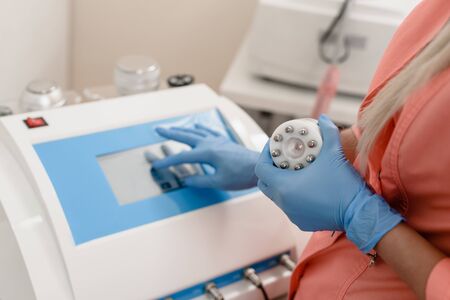 Closeup of cosmetologist using laser machine in beauty salonの写真素材